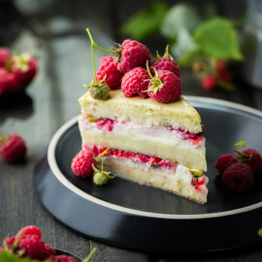 Raspberry pistachio layer cake on a black plate